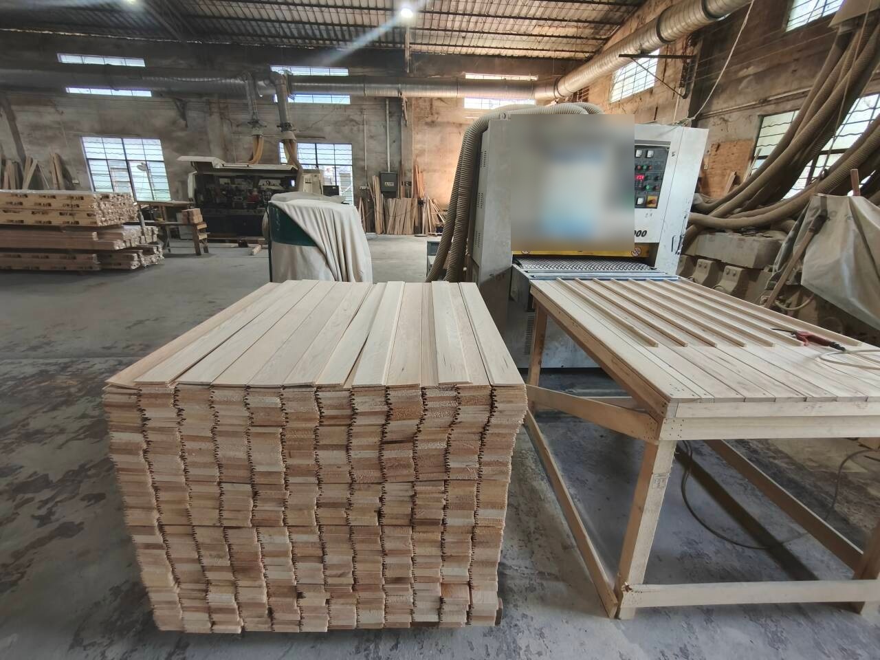 A sanding machine and stacked boards on the workshop floor